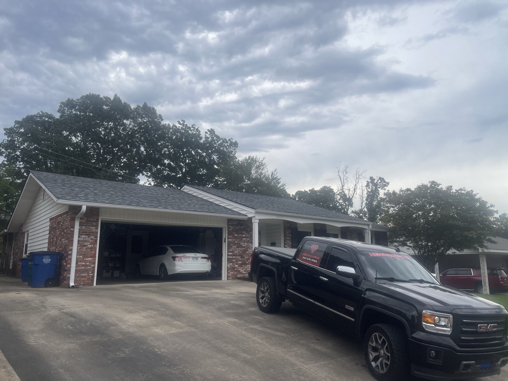 Completed roof replacement on a brick ranch home in Central Arkansas with the Hero Roofing truck in the driveway