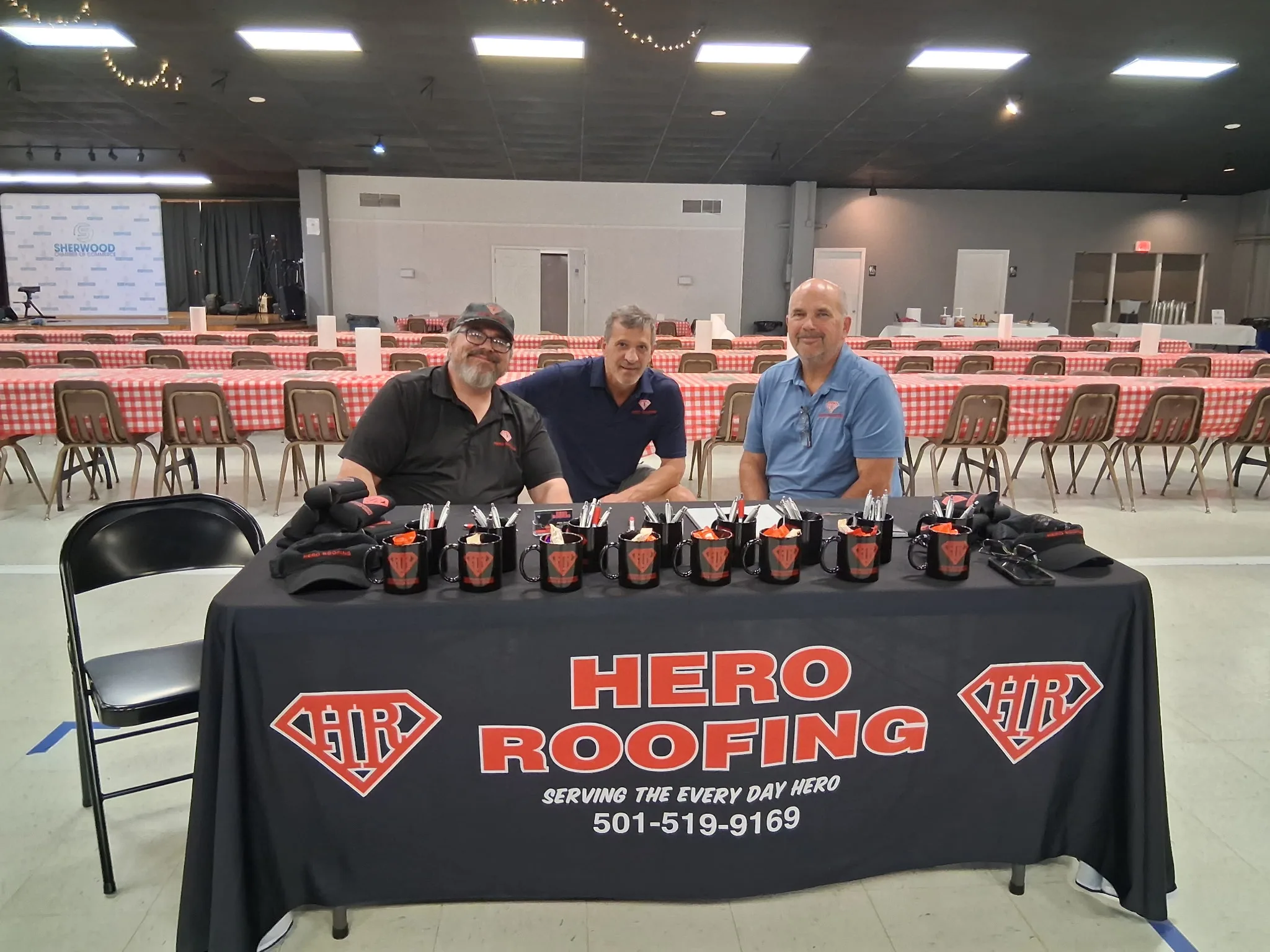 Three Hero Roofing team members behind the company table at the Sherwood Chamber’s 50th Annual Fish Fry
